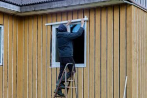 Blog Vanhook Roofing and Exteriors in Wylie, TX - Vanhook Roofing and Exteriors construction panel house finishing windows facade side worker installs metal slopes taps sunny autumn day 1 | Vanhook Roofing and Exteriors
